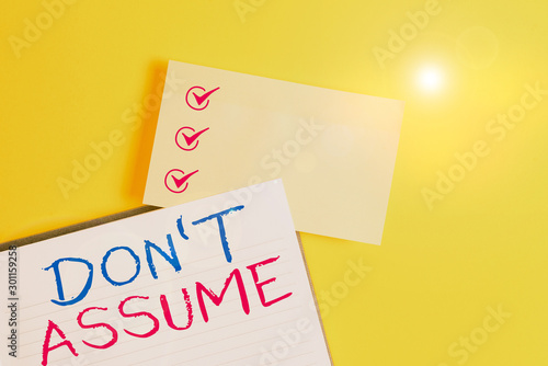 Conceptual hand writing showing Don T Assume. Concept meaning do not accept something to be true without question or proof Empty orange paper with copy space on the yellow table