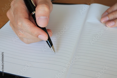 ノートにボールペンで書く手元のアップ © Sally B