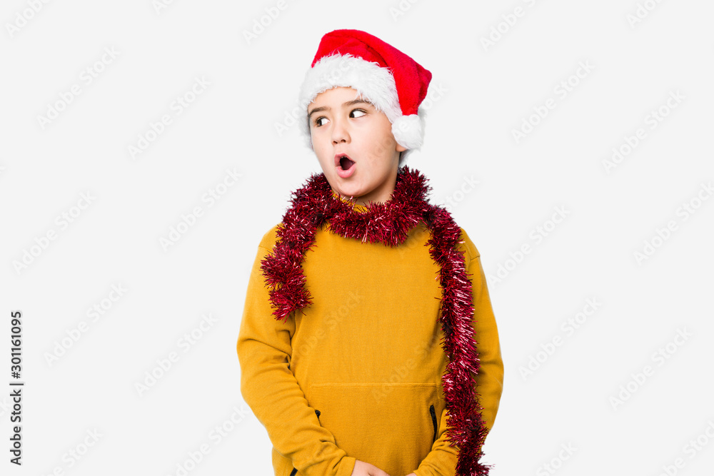 Little boy celebrating christmas day wearing a santa hat isolated being shocked because of something she has seen. Little boy celebrating christmas day wearing a santa hat isolated being shocked because of something she has seen.