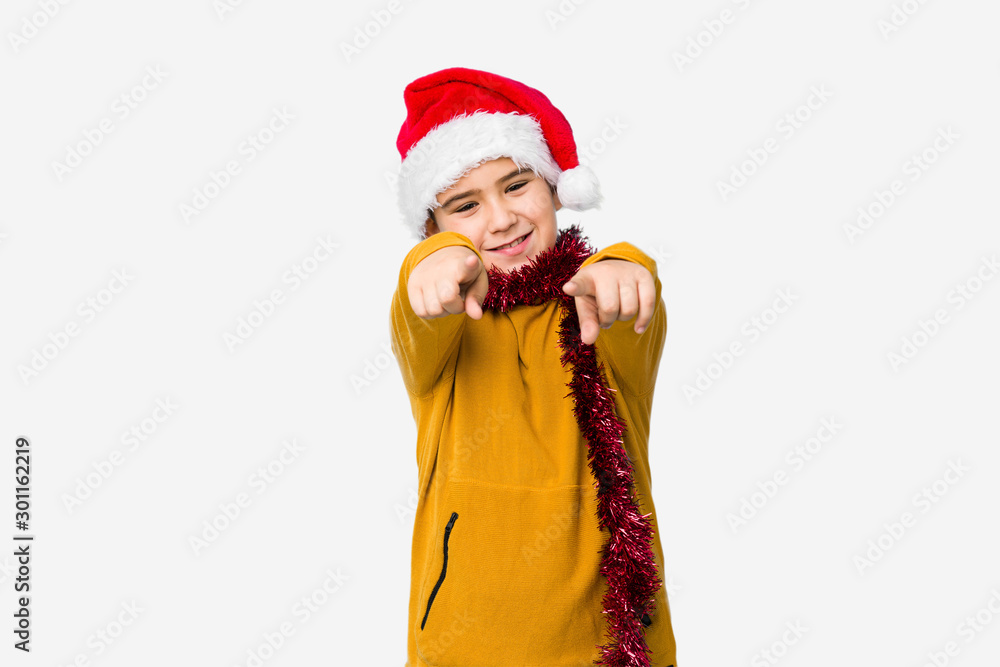 Little boy celebrating christmas day wearing a santa hat isolated cheerful smiles pointing to front. Little boy celebrating christmas day wearing a santa hat isolated cheerful smiles pointing to front.