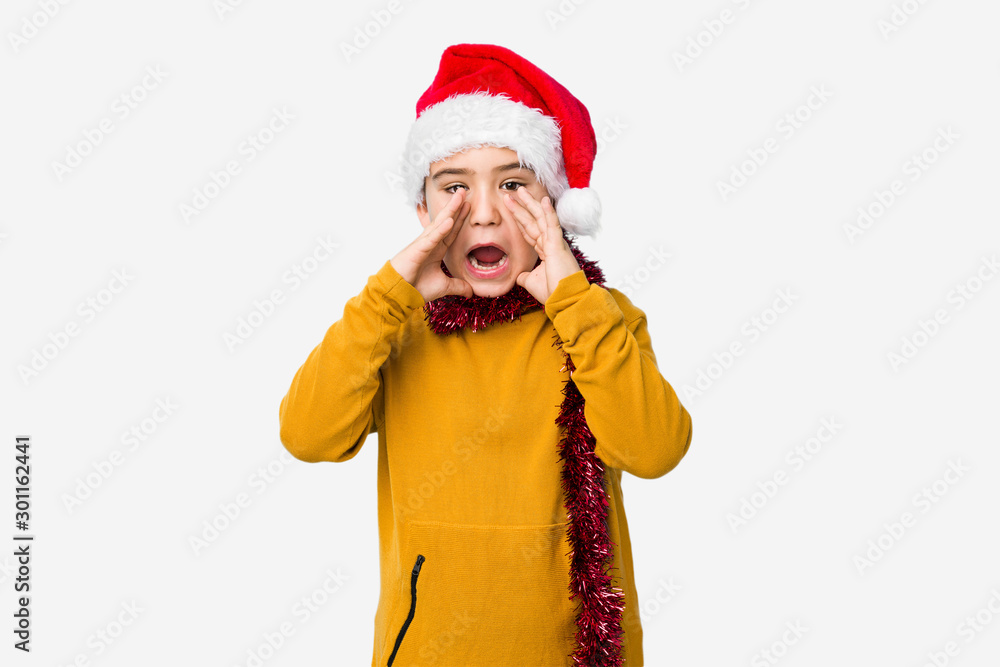 Little boy celebrating christmas day wearing a santa hat isolated shouting excited to front. Little boy celebrating christmas day wearing a santa hat isolated shouting excited to front.