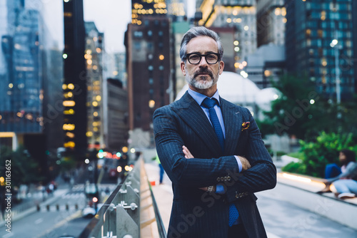 Photography Confident mature businessman with arms crossed against evening New York street