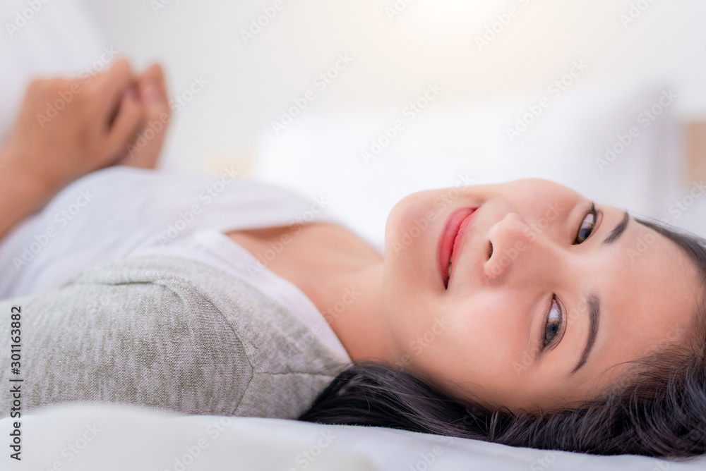 Beautiful young pretty Asian woman wake up and make happy smile with white shirt at the white bed in the morning. Beautiful young pretty Asian woman wake up and make happy smile with white shirt at the white bed in the morning.