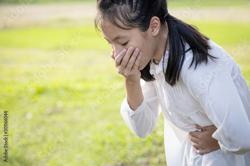 Fotografi Asian beautiful child girl covered her mouth about to throw up,vomit,puke retch
