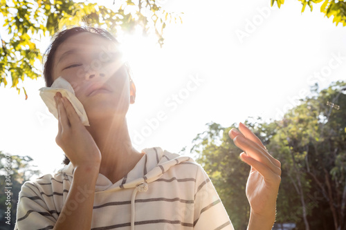 Photography Asian child girl wiping sweat on her face with tissue paper suffer from sunburn
