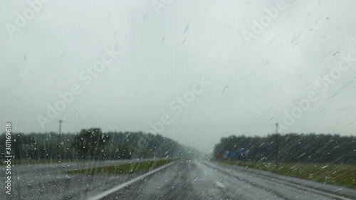 Сar is moving on road in rainy weather. Raindrops trickle down the windshield, which has nanocoating photo