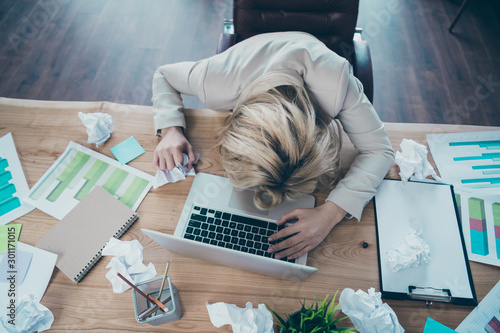 High angle above view photo of business lady head lying on desk listen online report crumple papers awful corporate situation sit chair formalwear blazer workplace office