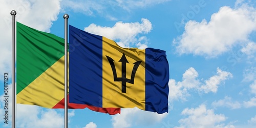 Republic Of The Congo and Barbados flag waving in the wind against white cloudy blue sky together. Diplomacy concept, international relations.