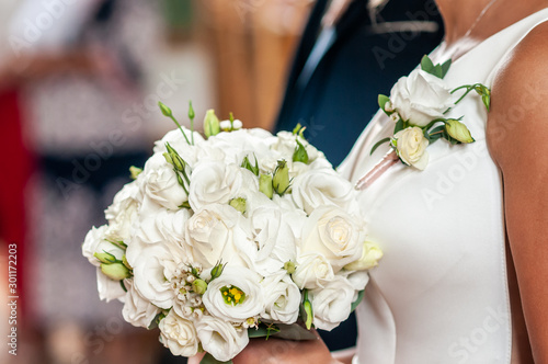 Groom and bride holding hands on the bouquet of flowers