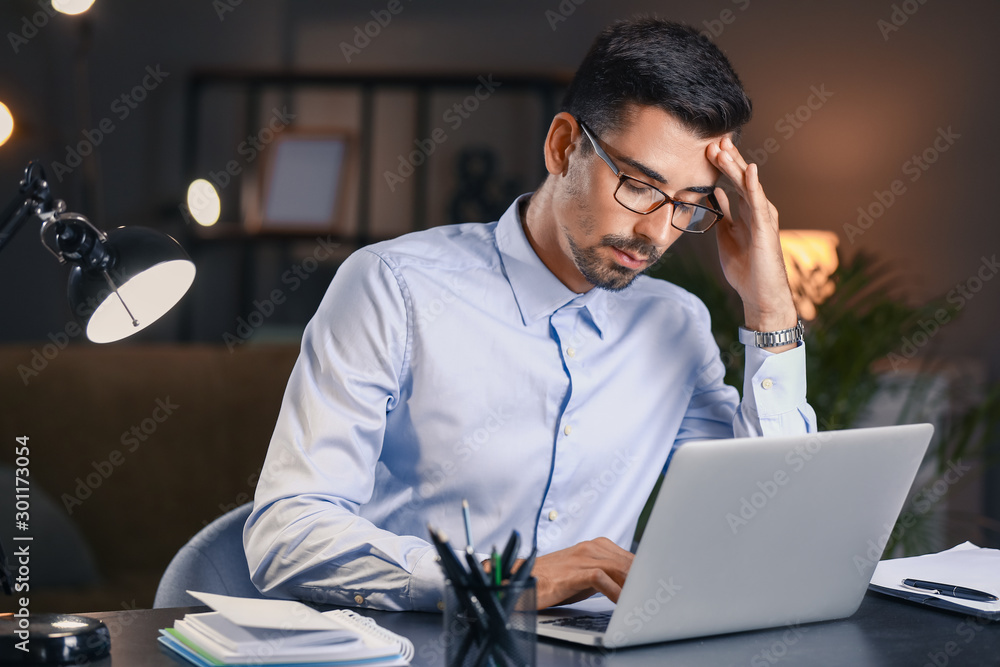 Tired businessman trying to meet deadline in office late in evening