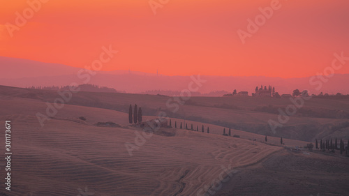 Beautiful sunset in Tuscany with the red sky over the rolling hills and Siena skyline at horizon. Pink hour. Travel destination Tuscany, Italy