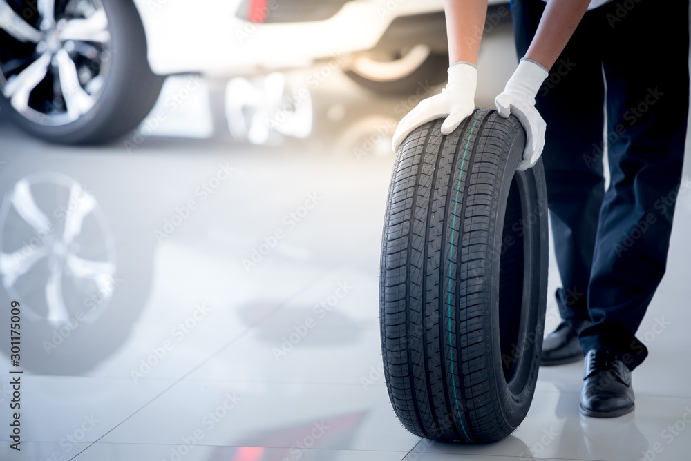 A car mechanic is in the process of checking new tires in stock for tire replacement at a service center or auto repair shop for the auto industry.