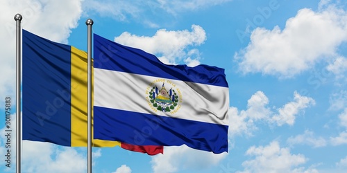 Romania and El Salvador flag waving in the wind against white cloudy blue sky together. Diplomacy concept, international relations.
