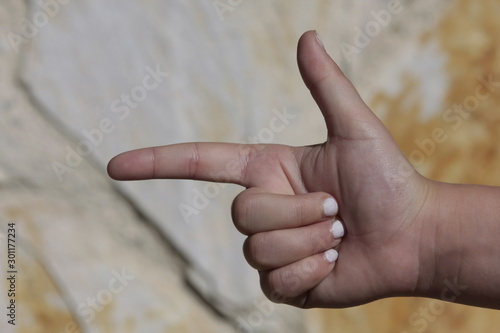 Mano de niña con las uñas pintadas de blanco realizando distintos signos.