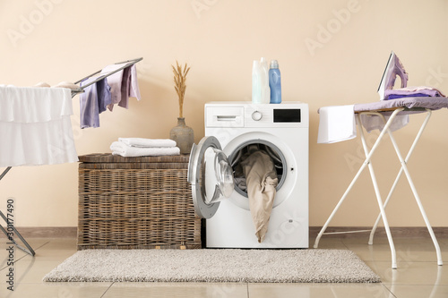 Принти на полотні Modern washing machine with laundry, clothes dryer and ironing board near color