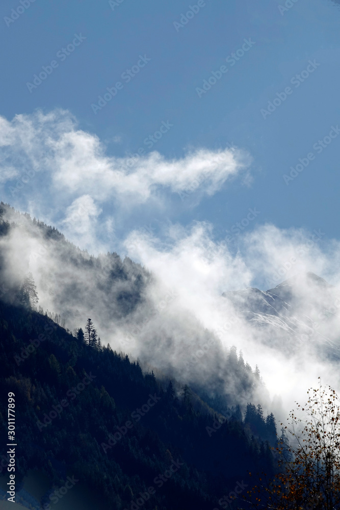 beautiful view to the alps with fog, clouds and fresh snow on the mountains in autumn