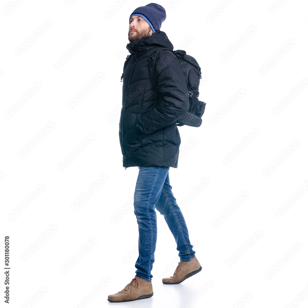 Fototapeta premium Man in winter jacket and warm hat, with backpack walking goes