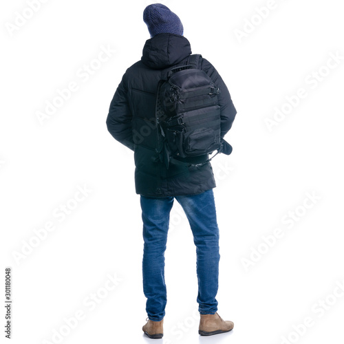 Man in winter jacket and warm hat, with backpack standing