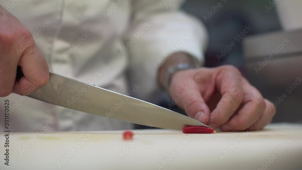 Closeup of chef hands cutting finely a red hot chilli pepper and take its chili seeds. Chef cooking in the restaurant. Closeup of chef hands cutting finely a red hot chilli pepper and take its chili seeds. Chef cooking in the restaurant.