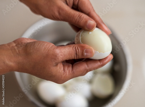 Peel Boiled Egg. Closeup of hand of Indian woman peeling a hard boiled egg in the kitchen. Egg recipe preparation process for background concept.