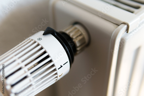 Heater thermostat valve set to snow flake frost icon, symbol for saving money at heating costs or low temperature