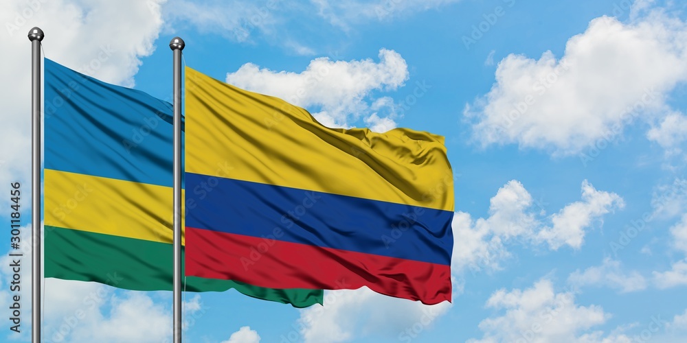Rwanda and Colombia flag waving in the wind against white cloudy blue sky together. Diplomacy concept, international relations. Rwanda and Colombia flag waving in the wind against white cloudy blue sky together. Diplomacy concept, international relations.