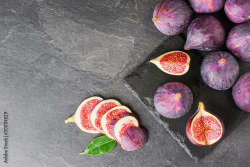 Figs fruits on dark stone table top view. Ripe fig citrus on black slate and texture background.