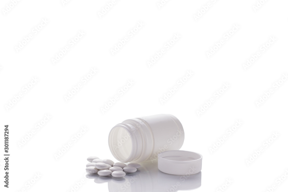 A bottle of pills lies on a mirror surface on a white background in the center with a place for text. A bottle of pills lies on a mirror surface on a white background in the center with a place for text.