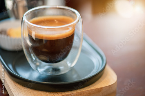 Hot espresso coffee in a clear glass, in retro coffee shop.