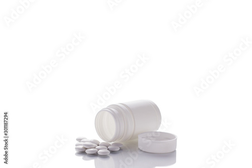 A bottle of pills lies on a mirror surface on a white background in the center with a place for text.