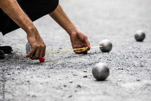 Man measuring the distance of petanque ball in petanque field