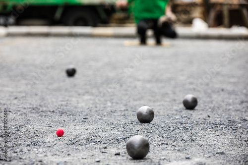 Petanque ball boules and small red jack on petanque field, Man playing petanque photo