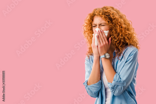 ill redhead woman sneezing with paper napkins, Isolated On pink photo