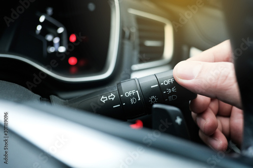 Obraz na plátne Young man hand adjusting headlight control switch with blur background