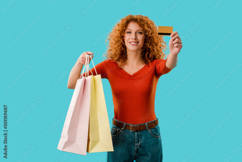 happy girl holding shopping bags and credit card, Isolated On blue - obrazy, fototapety, plakaty 