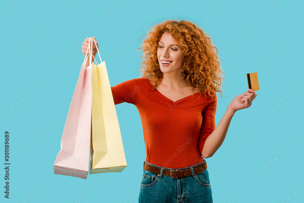 beautiful girl holding shopping bags and credit card, Isolated On blue - obrazy, fototapety, plakaty 