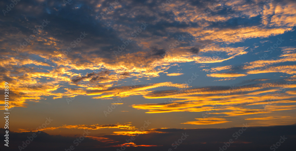 Panorama Sunlight with dramatic sky. Cumulus sunset clouds with sun setting down on dark background.Vivid orange cloud sky.