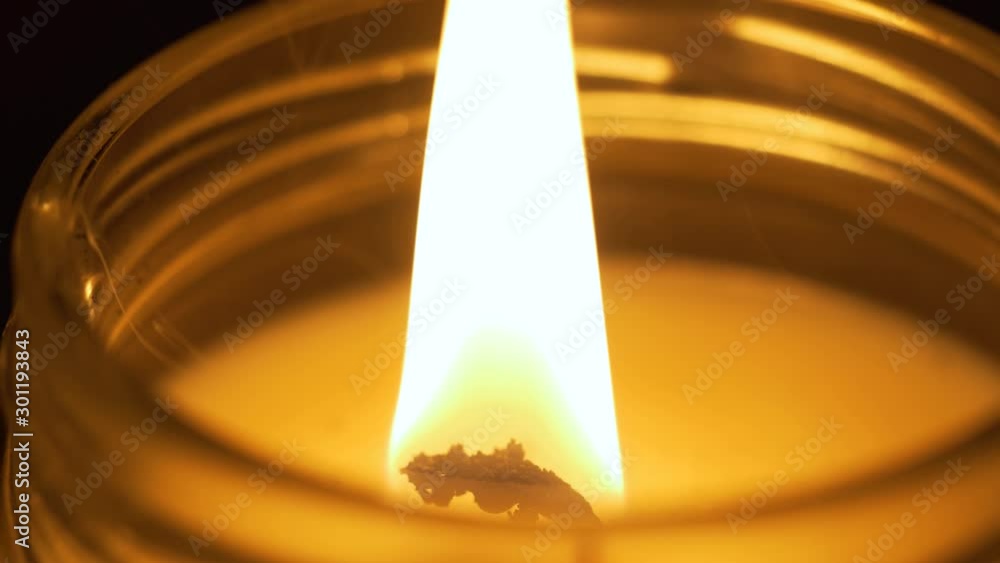 Close up of top of candle that is lit, wick pops and then is blown out