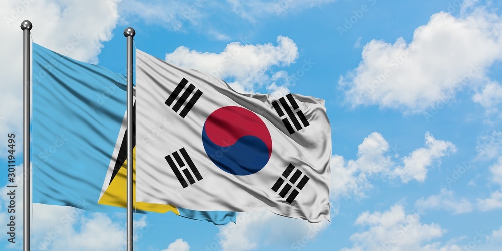 Saint Lucia and South Korea flag waving in the wind against white cloudy blue sky together. Diplomacy concept, international relations. Saint Lucia and South Korea flag waving in the wind against white cloudy blue sky together. Diplomacy concept, international relations.