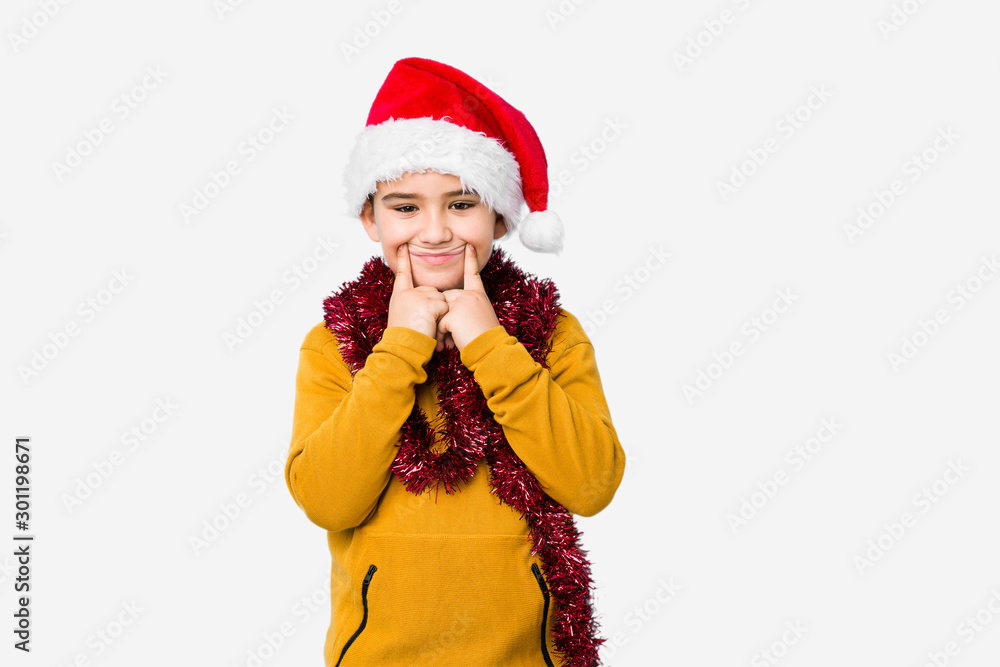 Little boy celebrating christmas day wearing a santa hat isolated doubting between two options. Little boy celebrating christmas day wearing a santa hat isolated doubting between two options.
