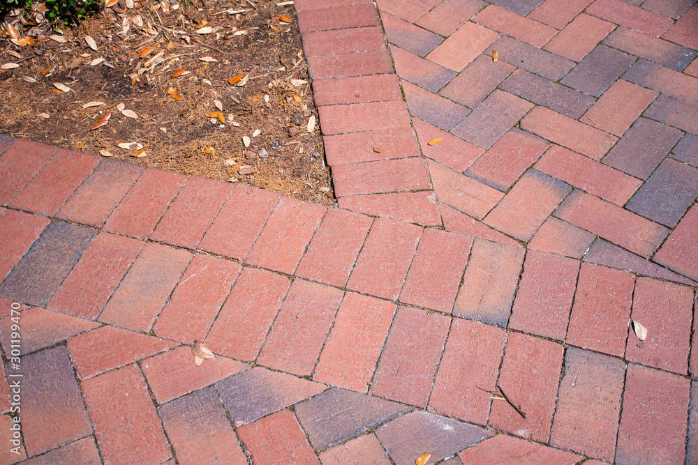 Fototapeta premium In Beaufort, South Carolina, this traditional Southern landscaping choice, of brick pavers in a herringbone pattern with a double soldier course provide a safe and durable walkway or patio surface.