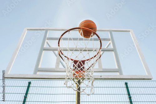 Basketball goes through the hoop on the sports field. © Andrii