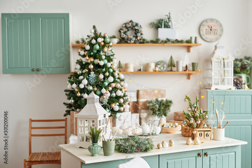 Interior light kitchen with christmas decor and tree. Turquoise-colored kitchen in classic style. Christmas in the kitchen. Bright kitchen in mint and white shades with Christmas. 