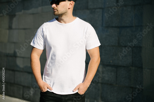 Man model with beard wearing white blank t-shirt and a baseball cap with space for your logo or design in casual urban style