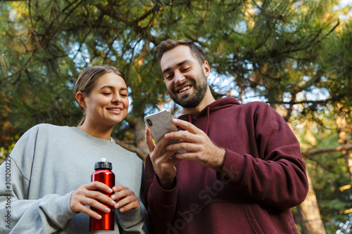 Happy positive sports woman and man using mobile phone