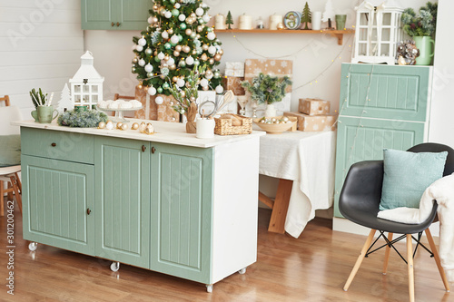 Interior light kitchen with christmas decor and tree. Turquoise-colored kitchen in classic style. Christmas in the kitchen. Bright kitchen in mint and white shades with Christmas. 