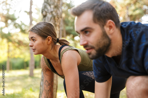 Photo of young serious couple doing exercises while working out