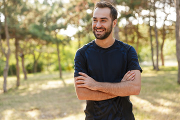 Sports man posing outdoors in nature green park.
