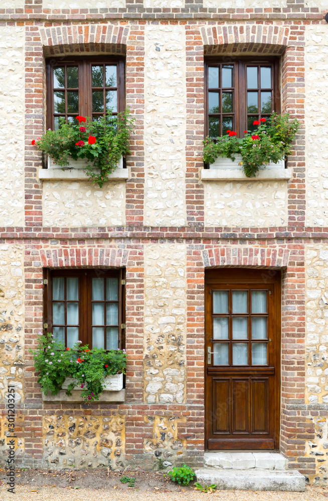 typical Normandy architecture house front with stone and brick facade and colorful flowerpots typical Normandy architecture house front with stone and brick facade and colorful flowerpots