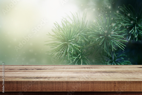 Christmas background. Blurred fir tree and empty wooden table.